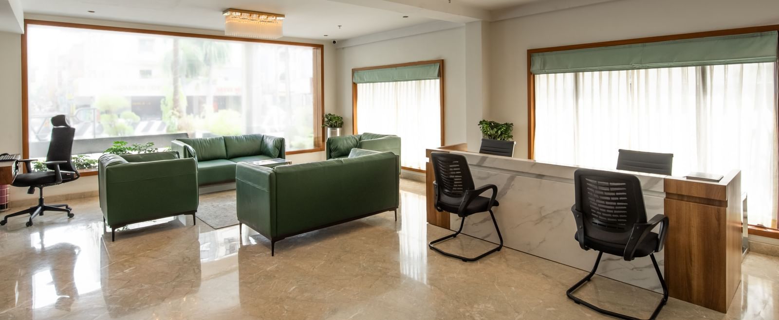 Spacious lounge area with sofas, chairs, and large windows at Hotel Royal Regency Chennai