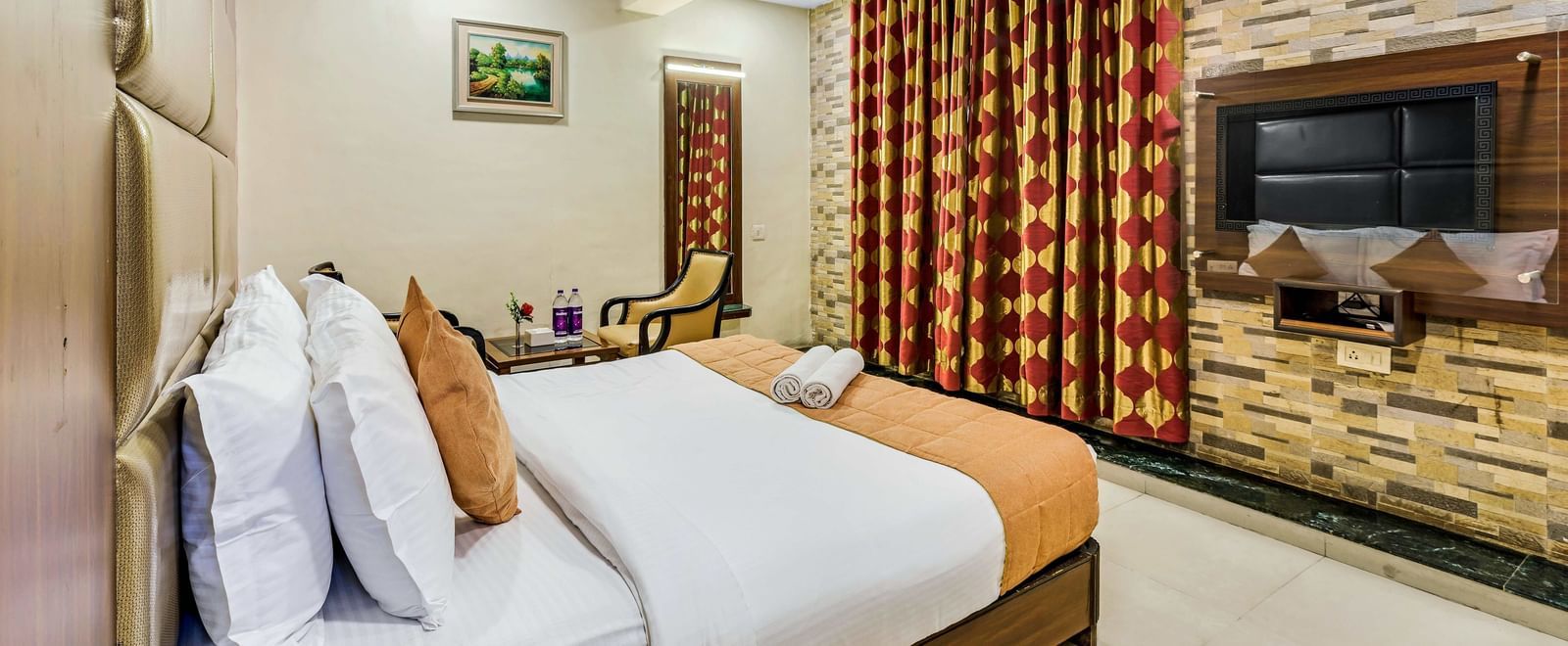 A brightly lit executive room in Krushnai Resort featuring a double bed with white lnen and yellow runner.