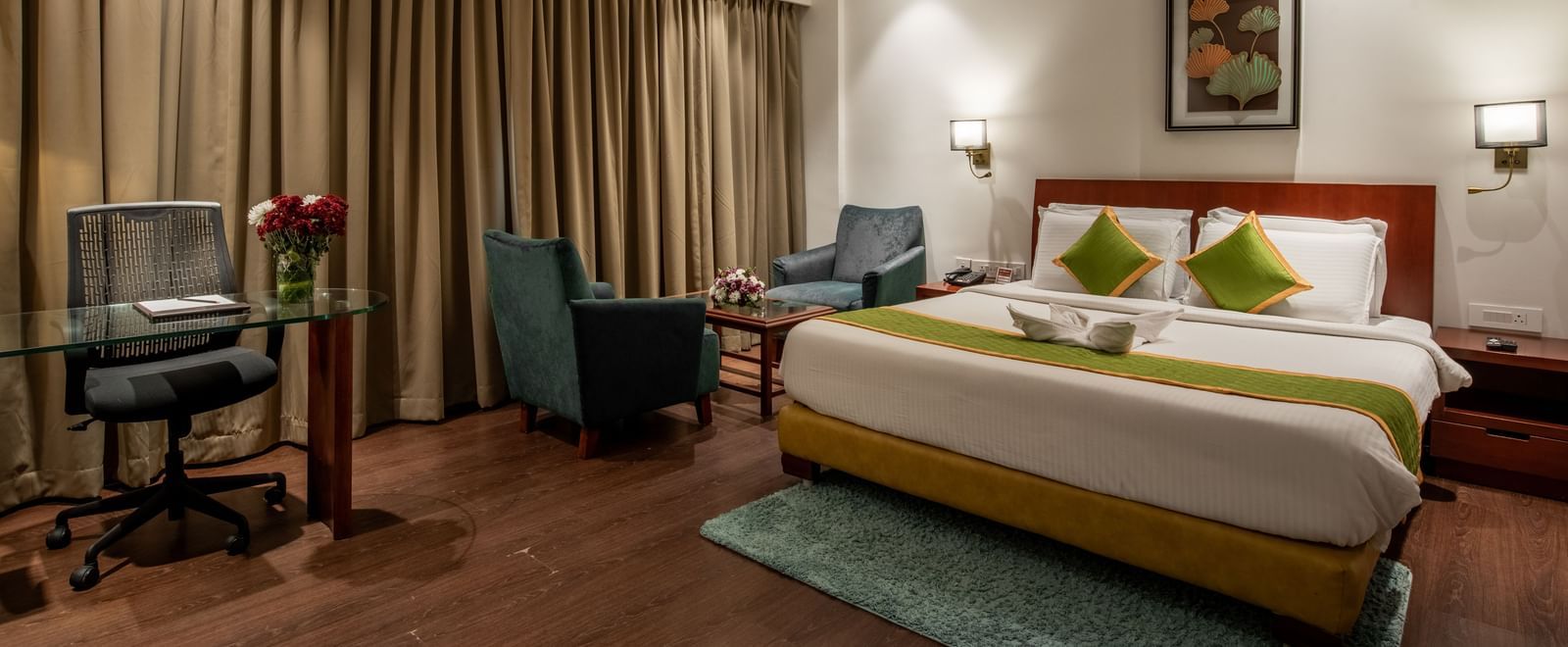 Bedroom with work desk, armchairs, and elegant curtains at Hotel Royal Regency Chennai