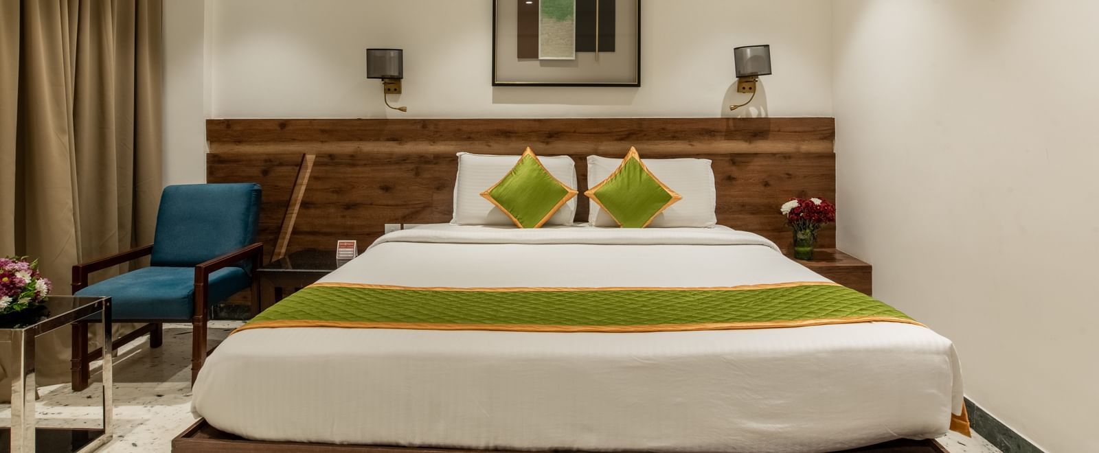 Guest room with king size bed, seating area, and framed artwork at Hotel Royal Regency Chennai