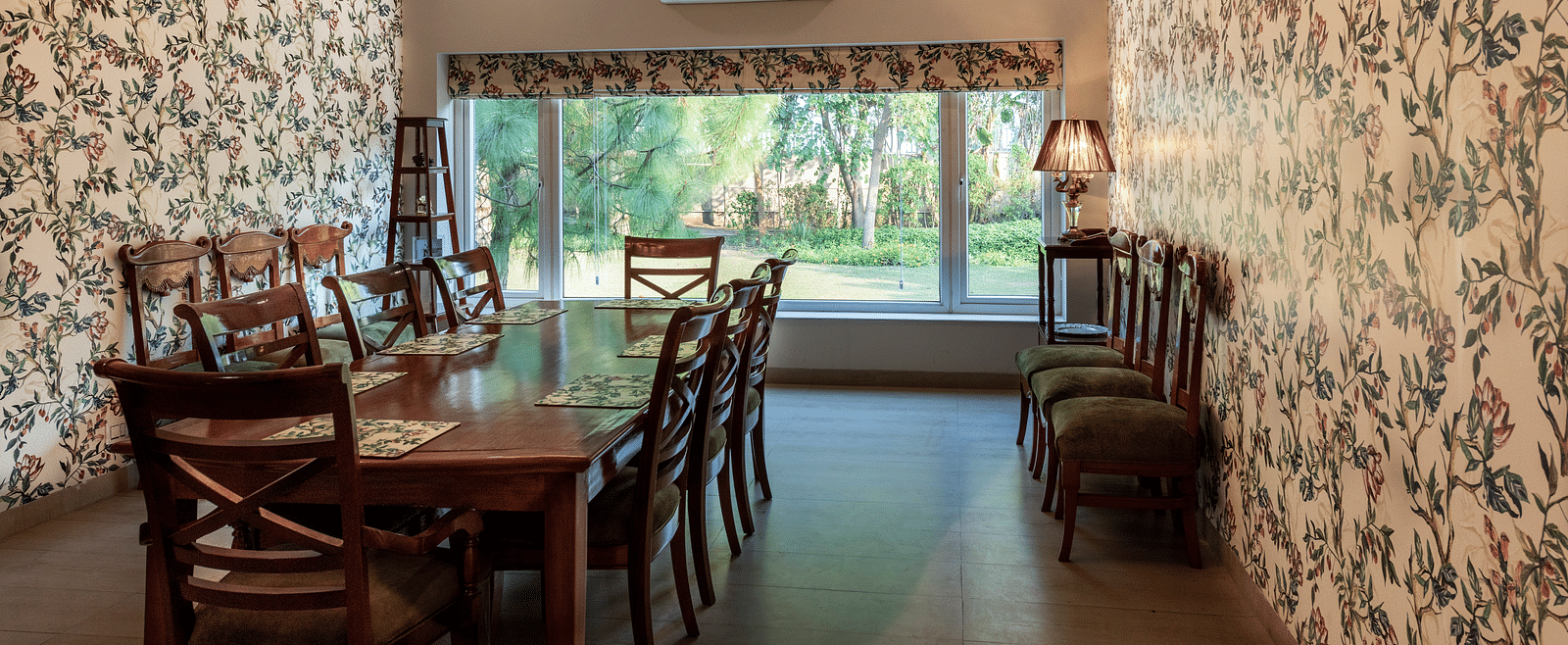 An image of a dining room with floral walls, a chandelier and an AC in the background.