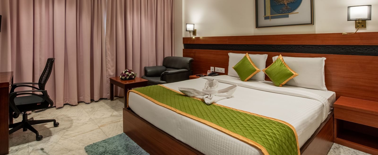 Room with king size bed, work desk, and pink curtains at Hotel Royal Regency Chennai
