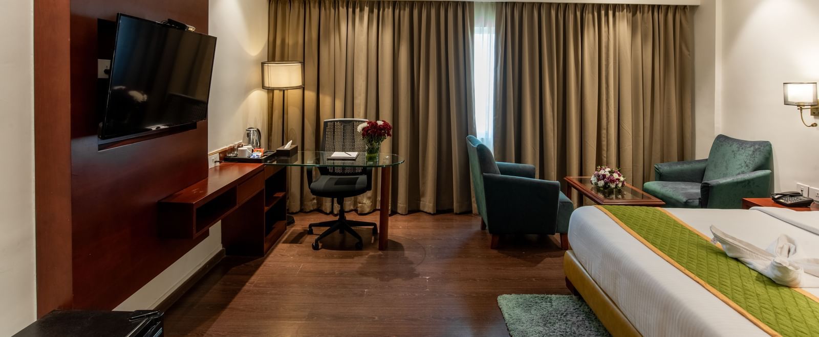 Spacious room with king size bed, television, and wooden flooring at Hotel Royal Regency Chennai