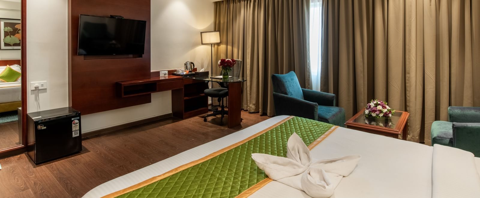 Modern guest room with bed, television, and comfortable seating at Hotel Royal Regency Chennai