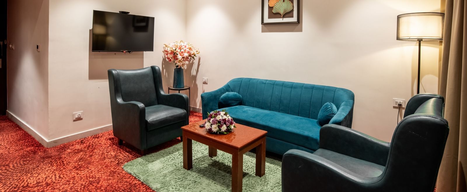 Living area with sofa seating, television, and floor lamp at Hotel Royal Regency Chennai