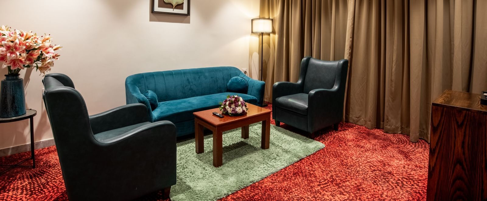 Spacious sitting area with sofa and armchairs in a suite at Hotel Royal Regency Chennai