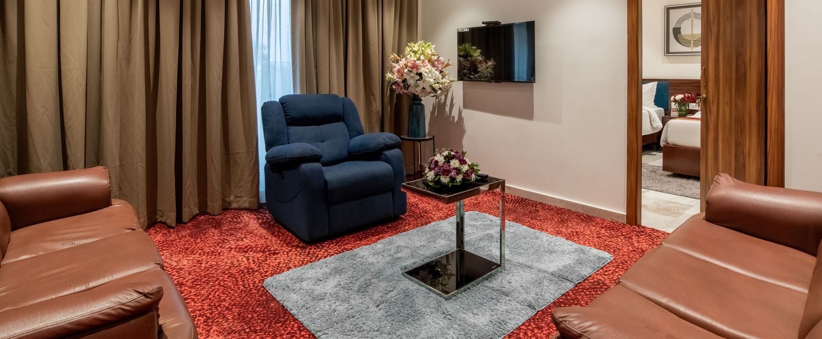 Comfortable lounge area with sofas, armchairs, and TV in a suite at Hotel Royal Regency Chennai