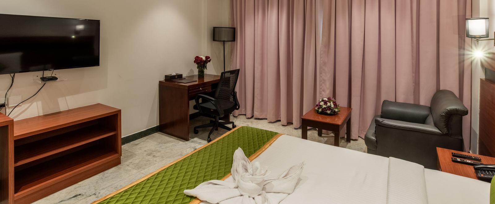 Well-furnished guest room with king size bed, sofa, and bedside lamps at Hotel Royal Regency Chennai