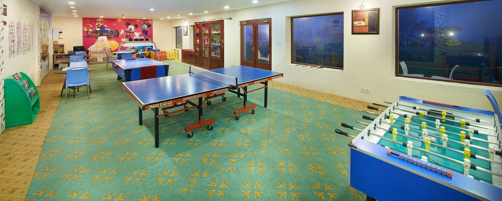 Indoor game room at Accord Highland Ooty with multiple table tennis tables and a foosball table
