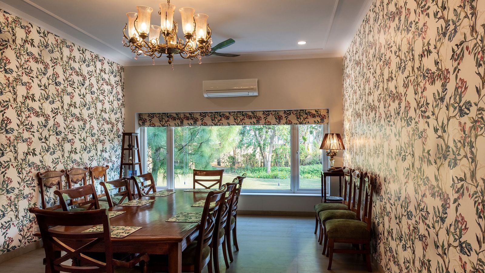 An image of a dining room with floral walls, a chandelier and an AC in the background.