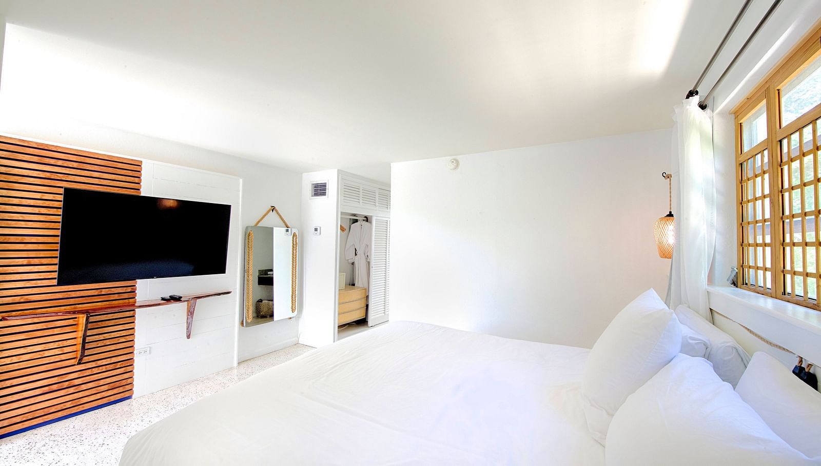 Bright bedroom at Casa Morada featuring a white bed, wall-mounted TV, and sliding wooden doors.