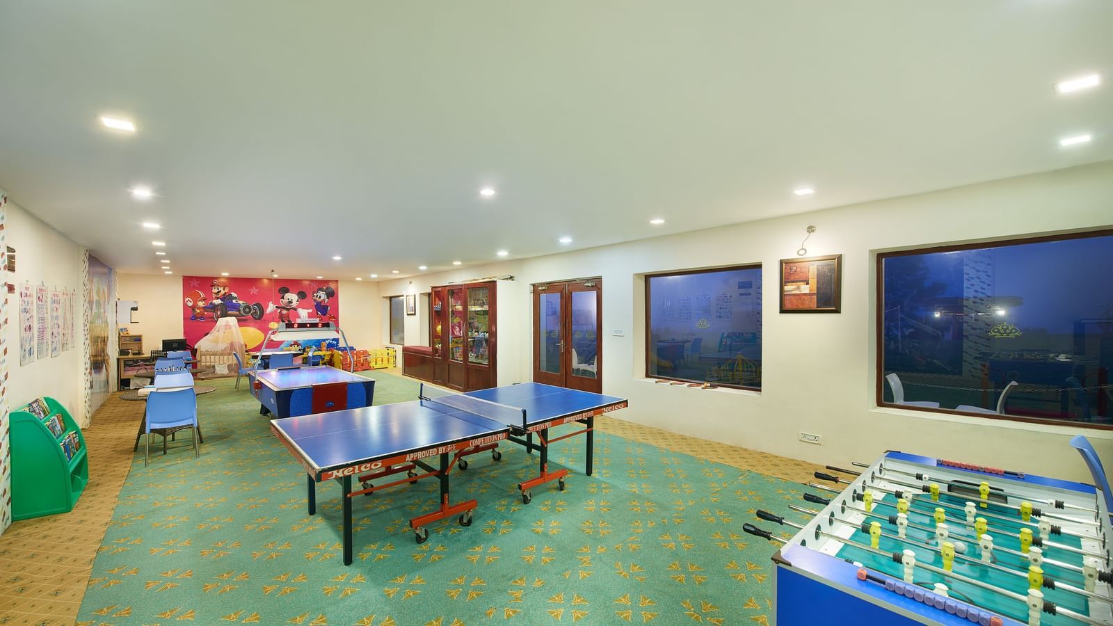 Indoor game room at Accord Highland Ooty with multiple table tennis tables and a foosball table