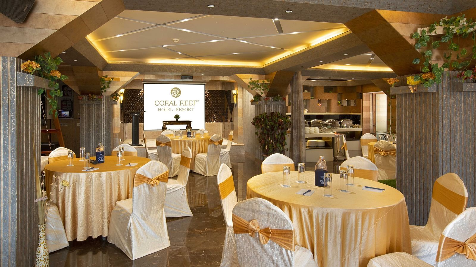 Image of tables arranged along with chairs in circles and a projector screen in the background at Mosaic Hall at Coral Reef Hotel and Spa in Port Blair