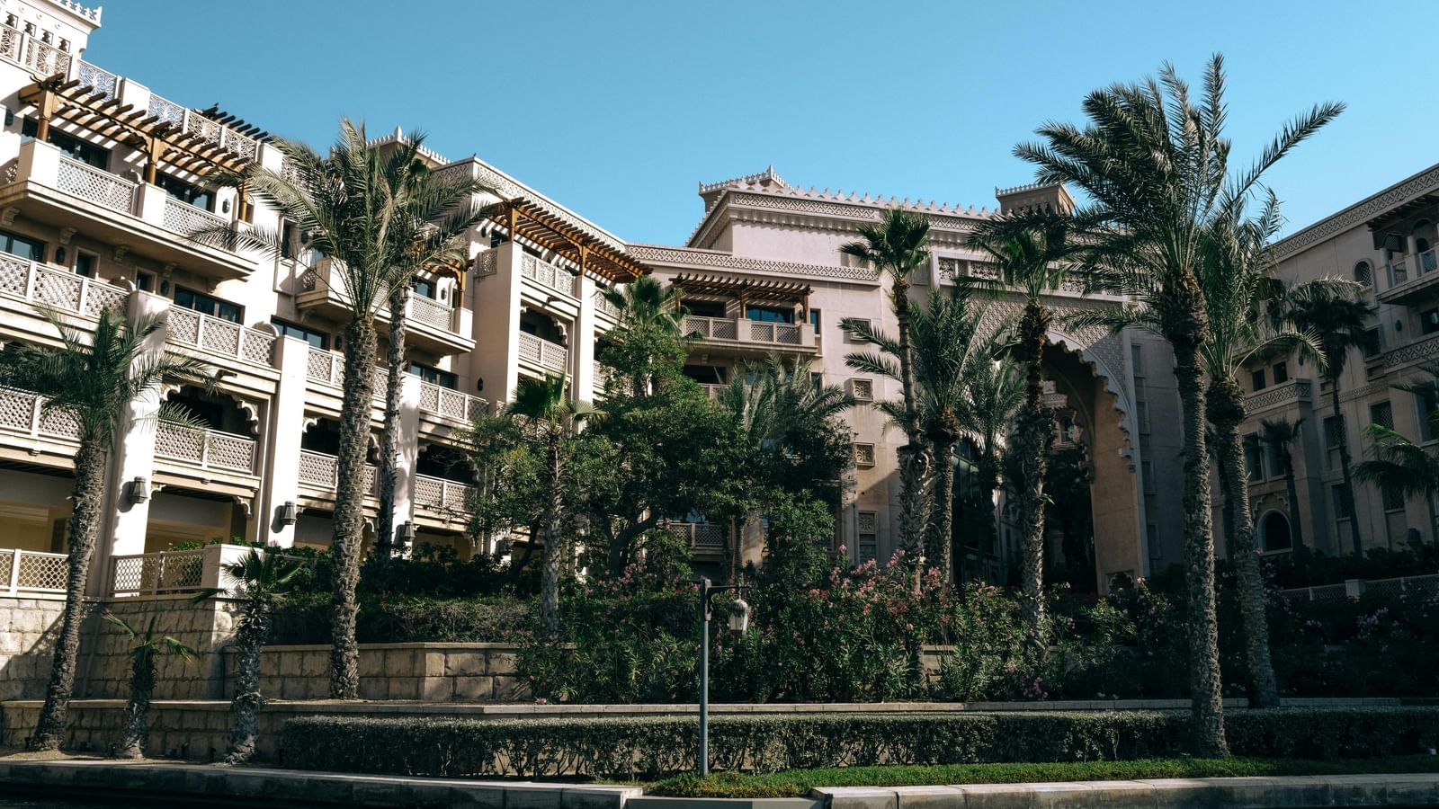 An exterior view of a residential or resort building with palm trees and balconies.