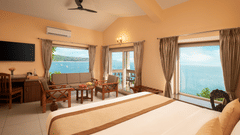 A view of a room at Highland Sarovar Portico, Sindhudurg, featuring a bed, a seating area and a balcony with views of the ocean - Stay in Sindhudurg