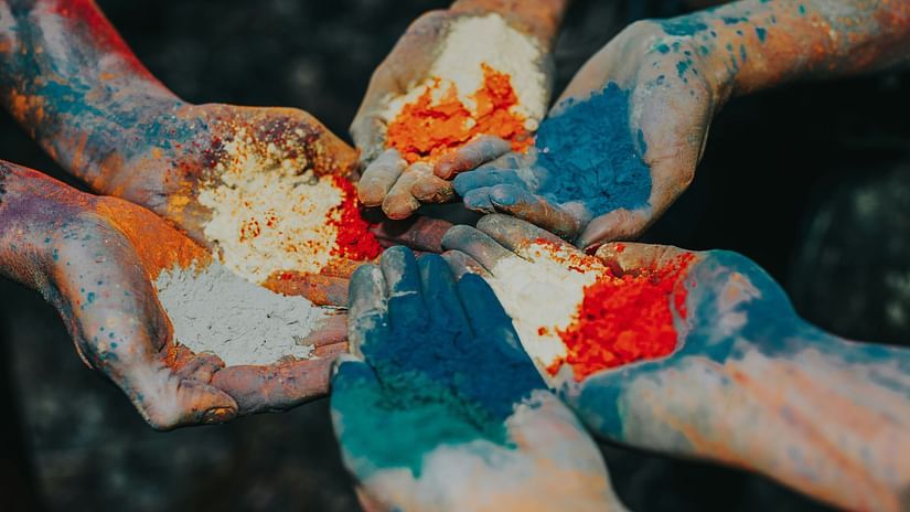 Hands clasped together, covered in vibrant Holi colors, celebrating the festival of love and spring. 