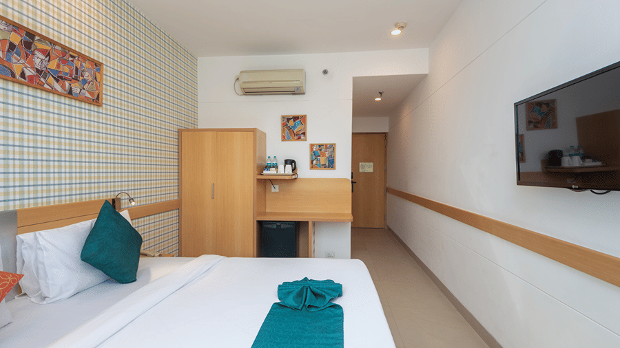 Room with a bed featuring green towel art and framed wall artwork at Mango Grove Hotel.