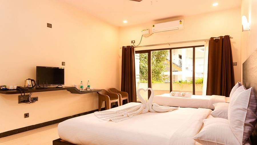 A double bed with a tv opposte it inside deluxe ac room - Mastiff Select Terrain