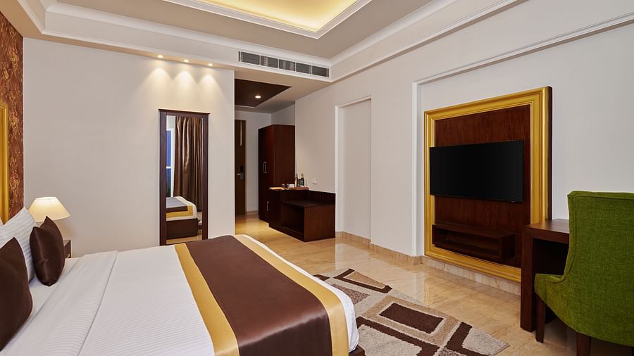 an armchair, a television, a double bed, and other amenities in the SUPER DELUXE ROOM - Royal Kingdom Sarovar Portico, Pilibhit