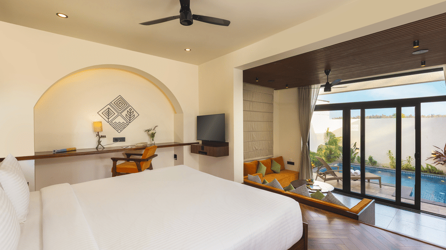 bedroom with a large bed, a ceiling fan, and a sliding glass door opening to an outdoor pool at The Golden Tusk, Jim Corbett