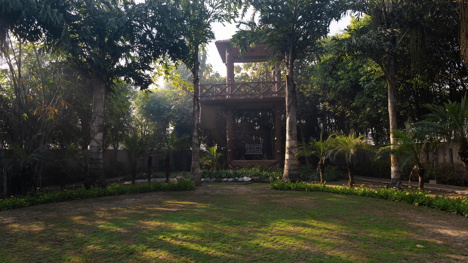 An image of a garden surrounded by tall trees at BluSalzz Resort.