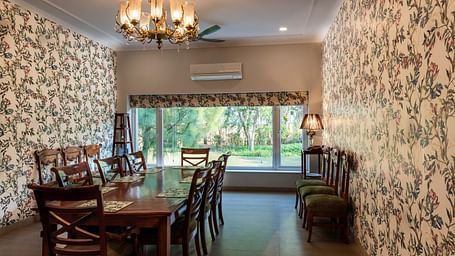 An image of a dining room with floral walls, a chandelier and an AC in the background.