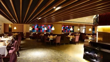 A wide-angle shot of a hotel restaurant at The Royal Comfort, with elegant lighting, tables set for dinner, and a warm atmosphere.