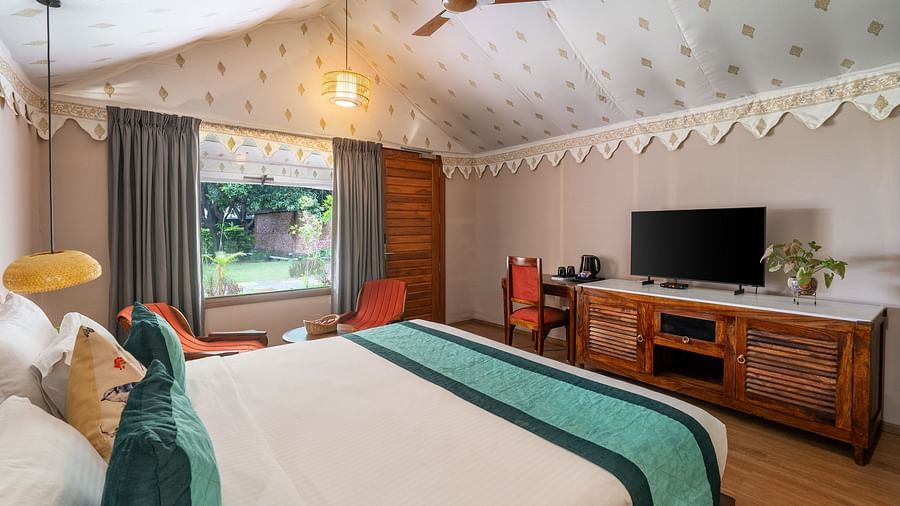 image of a beautiful luxury tent villa at aranya vilas featuring a king size bed with a tv table and television right opposite to it