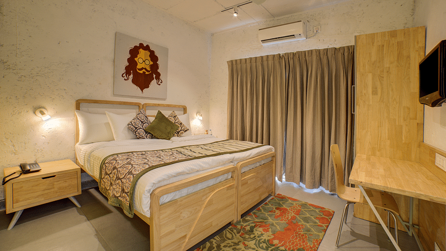 A large bedroom with a large bed with two side drawer and side lamps facing a television - Bedzzz, Rishikesh