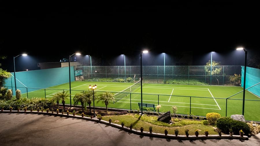 A view of a well-lit tennis court at BluSalzz Resort.