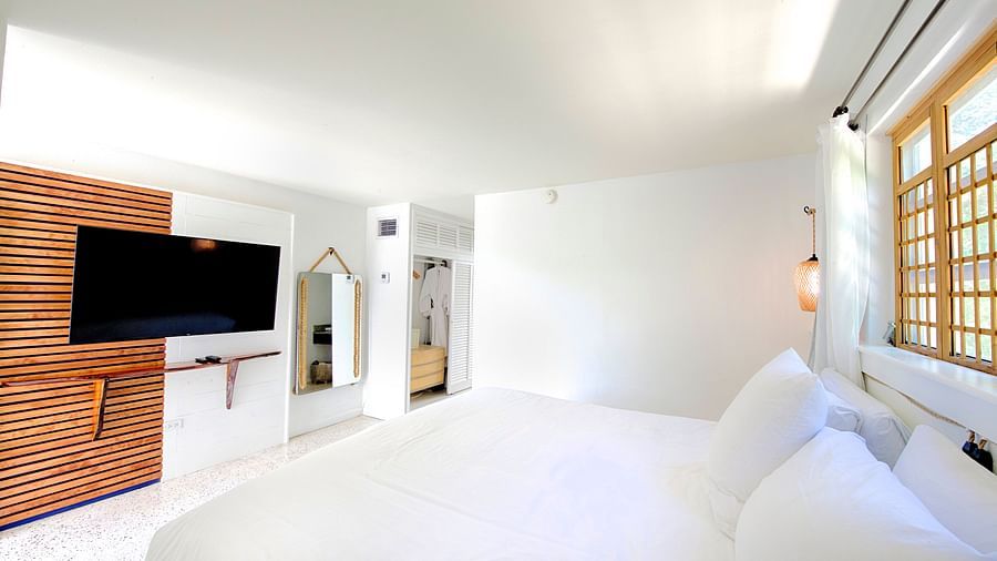 Bright bedroom at Casa Morada featuring a white bed, wall-mounted TV, and sliding wooden doors.