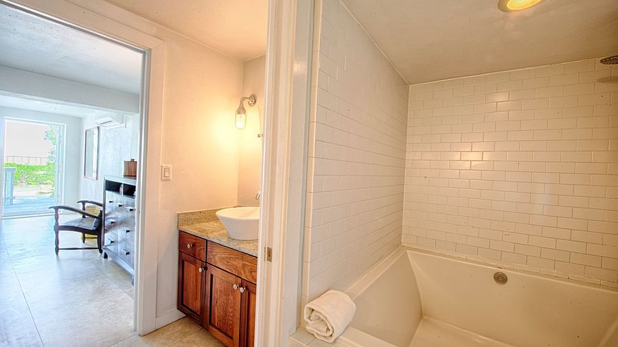 Bathroom at Casa Morada with a white tub, tile walls, and an adjacent vanity with sink.