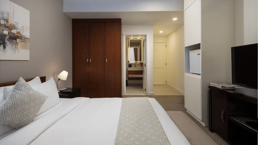 Studio with Workspace at Central Mansions, Phnom Penh featuring a queen bed, dedicated work desk, television, and kitchenette.