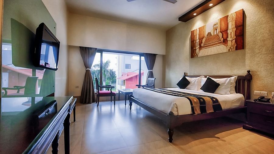 Club Room at Crescent Resort, Sehore featuring a plush bed facing a TV mounted on the wall and a sitting space next to the large window