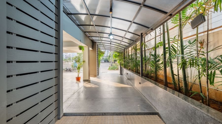 The outdoor entrance and walkway of Destino by Monday Hotels, Gachibowli, featuring a covered pathway lined with plants.