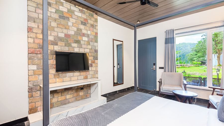 Closeup view of Luxury Cottage at DLS Divine River Resort and  Spa featuring a king size bed with mirror, TV and a chair.