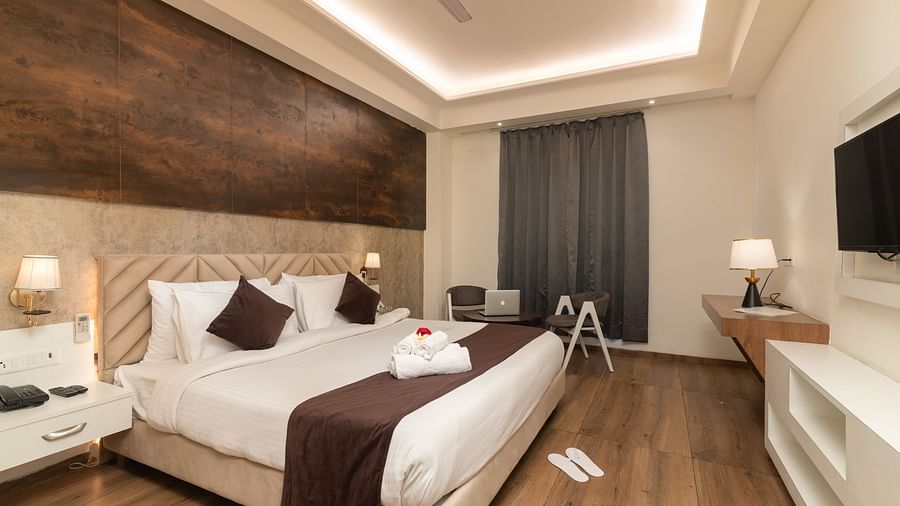 An image of a deluxe room with a work desk, chair, bed, flat screen TV, and other room amenities - DLS Ganga Bliss, Haridwar