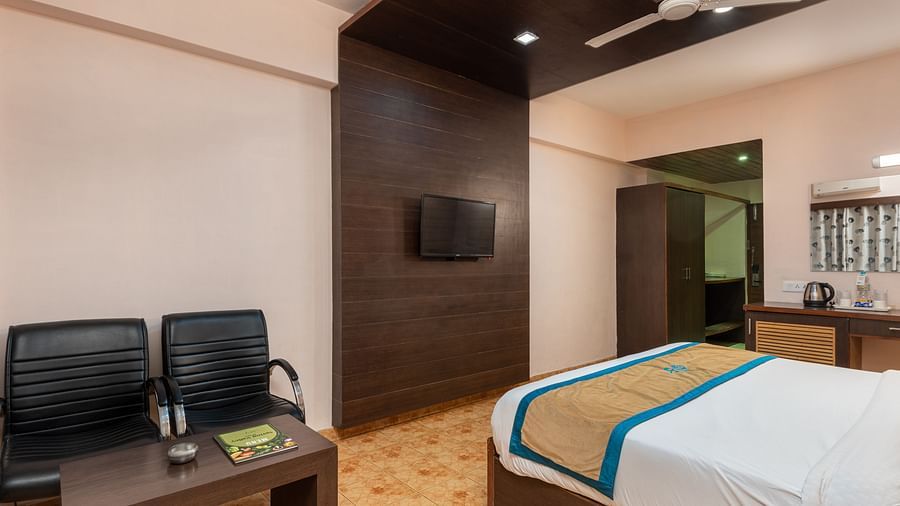 A Deluxe Non view room at DLS Spring Valley resort  Dharamshala featuring a  king bed, table, chairs and a TV