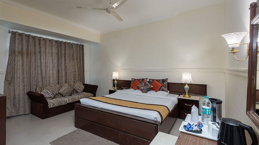 A wide angle shot of the king size bed inside a room featuring a couch | DLS The Pearl