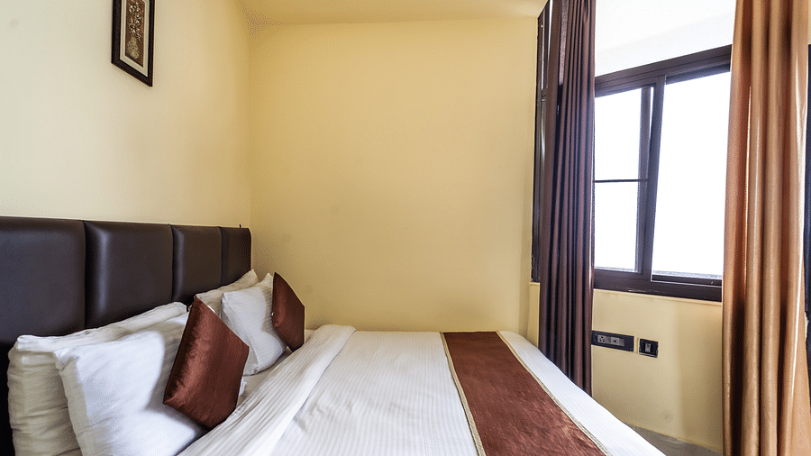 a bed placed by an open window at Flutter Hotels & Resorts