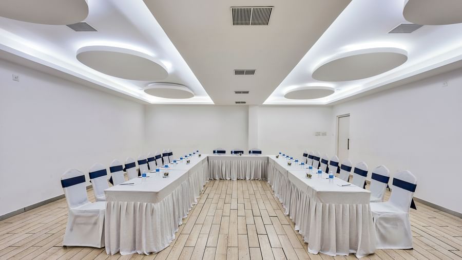 Conference hall setup with rows of tables and white chairs facing forward at Grande Bay Resort & Spa.
