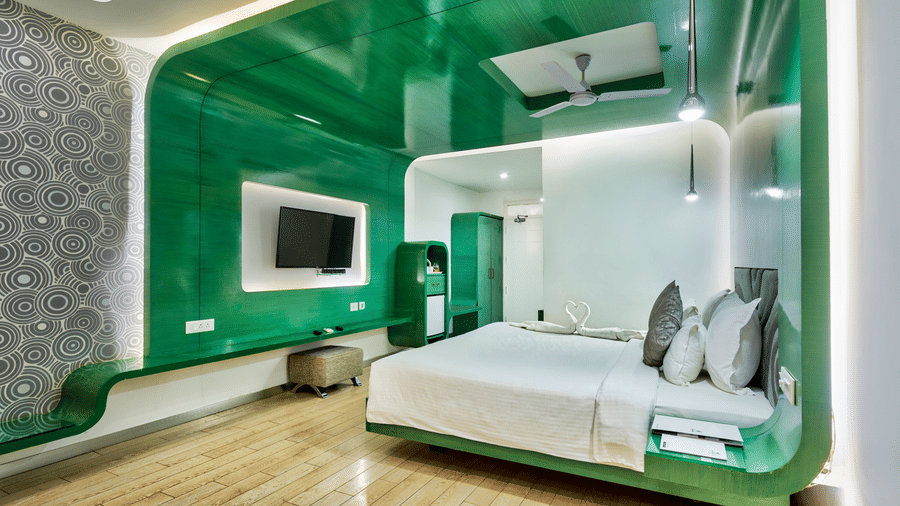A room with a king bed, green wall panel, and a television for a comfortable stay Mahabalipuram - Grande Bay Resort & Spa, Mamallapuram.