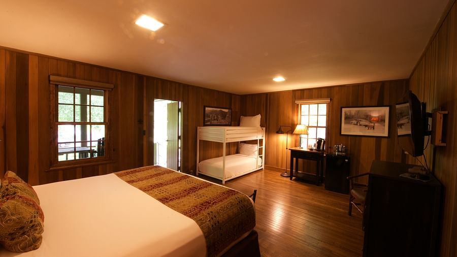 corner view image of a dimly lit bedroom featuring a double decker bunk bed and a double bed - Historic Tapoco Lodge