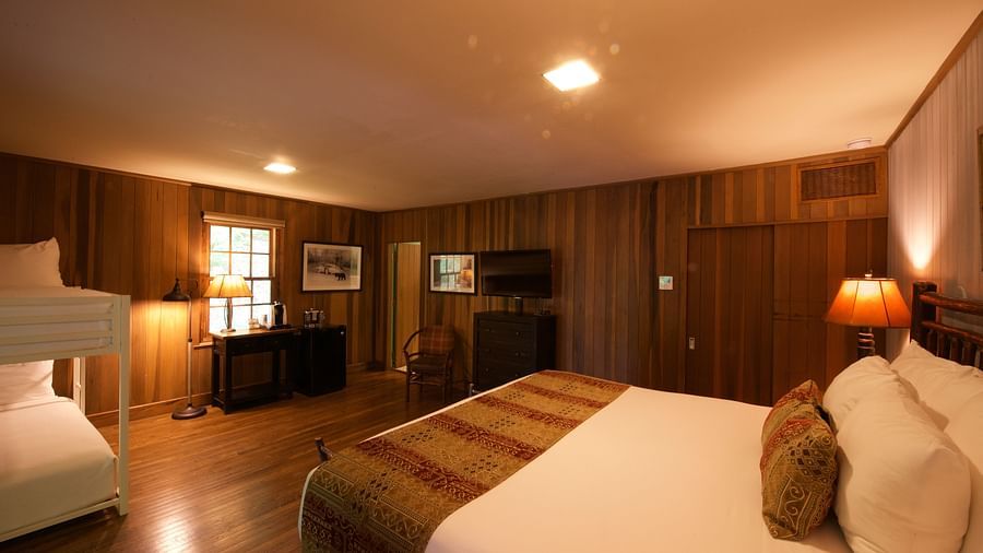a cozy image of a bedroom with wooden interiors and featuring a double bed and a small window right opposite to it - Historic Tapoco Lodge