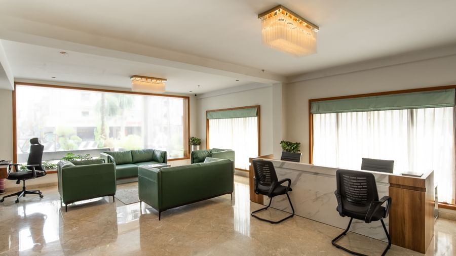 Spacious lounge area with sofas, chairs, and large windows at Hotel Royal Regency Chennai