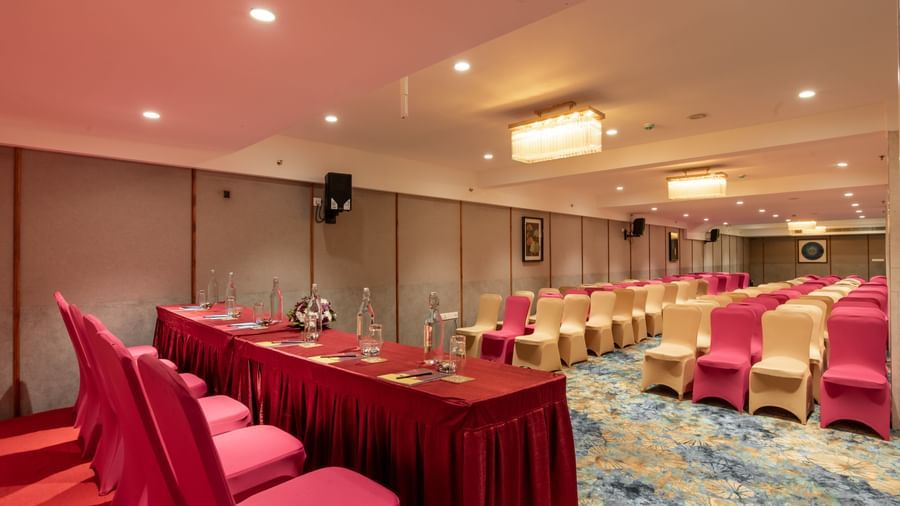 Hall with long table arrangement and red chair covers at Hotel Royal Regency Chennai