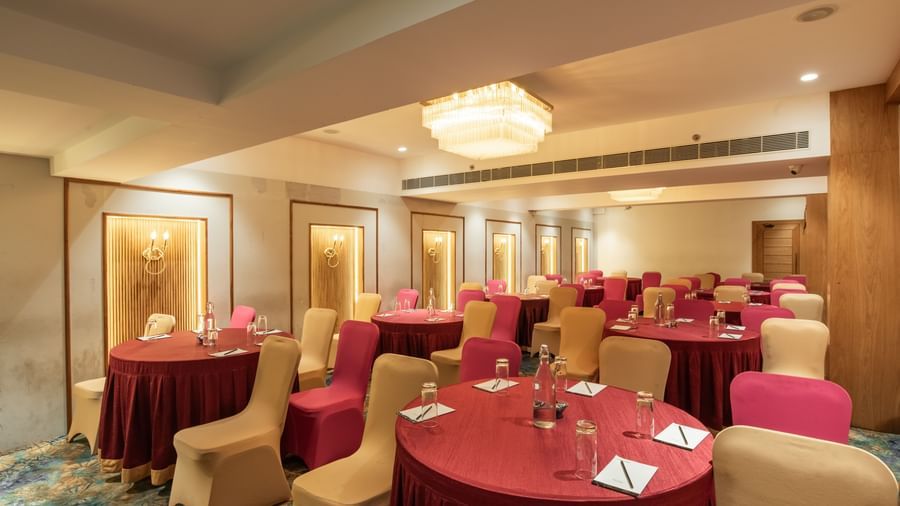 Event hall with round tables covered in red tablecloths at Hotel Royal Regency Chennai