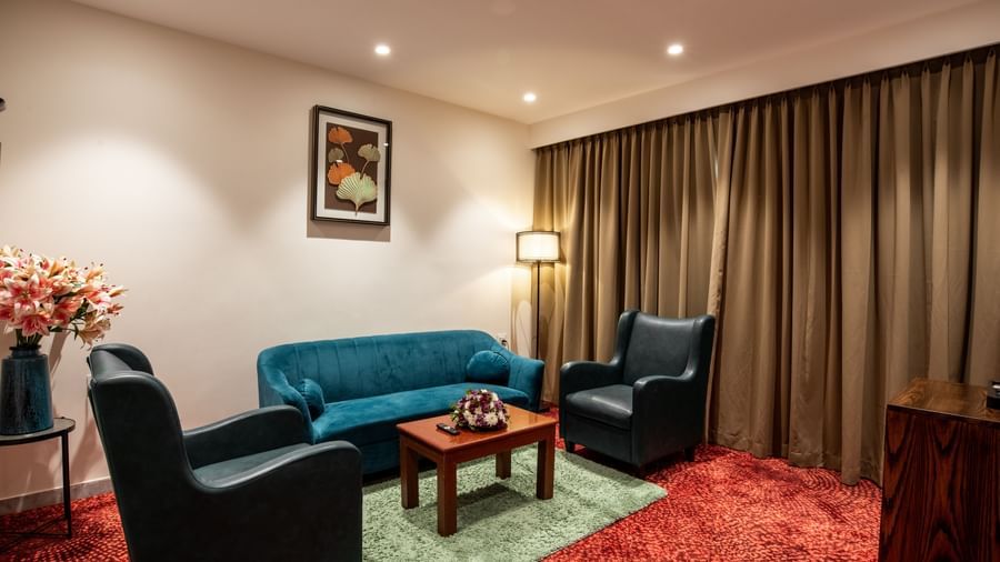 Spacious sitting area with sofa and armchairs in a suite at Hotel Royal Regency Chennai