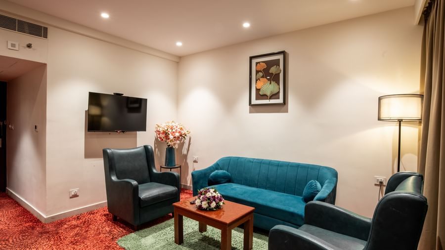 Living area with sofa seating, television, and floor lamp at Hotel Royal Regency Chennai