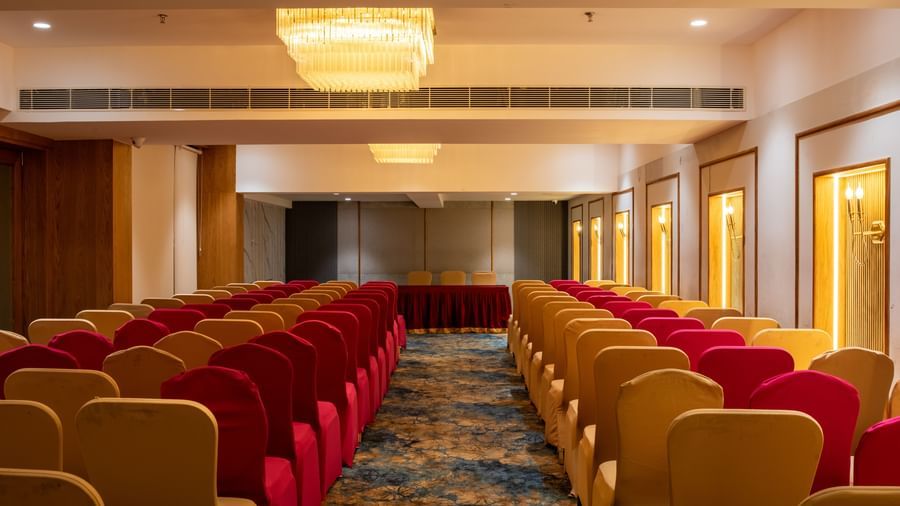 Banquet hall with seating in red and beige chairs at Hotel Royal Regency Chennai